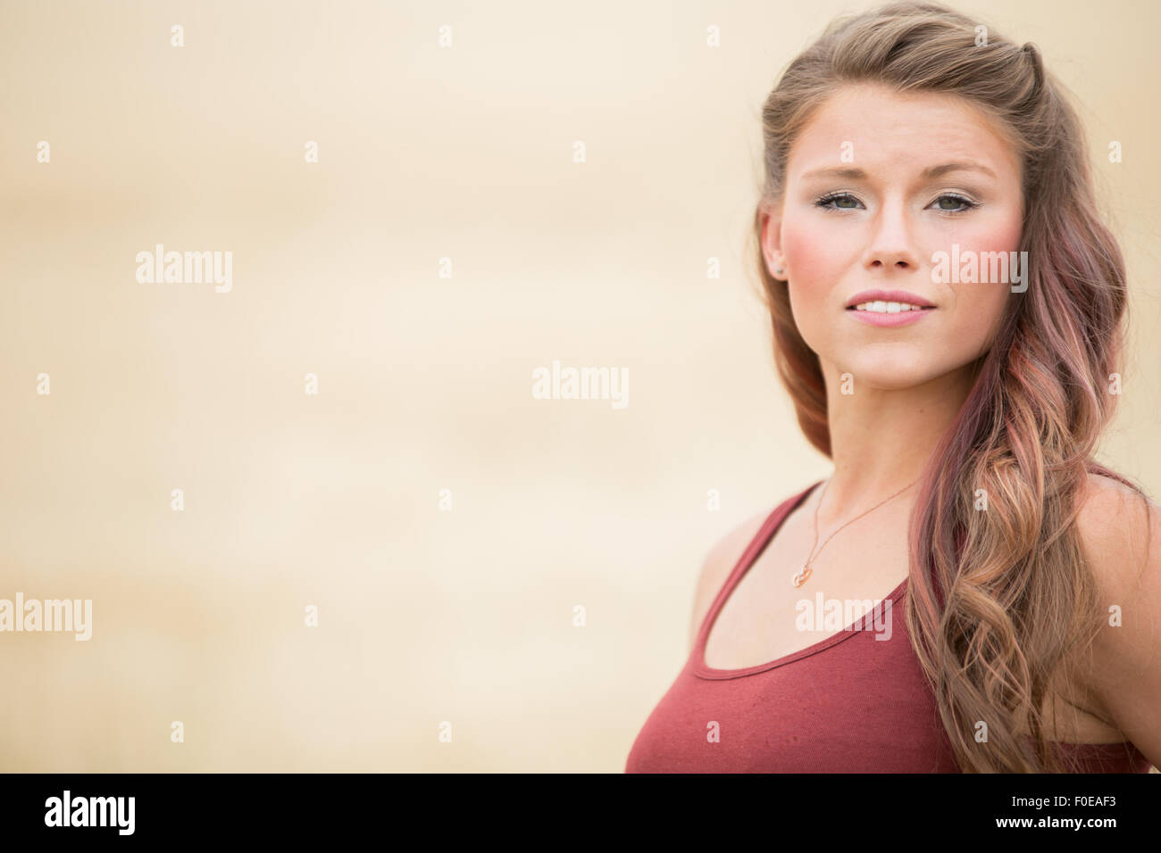 Young woman posing in large wheat field wearing red tank top. Stock Photo