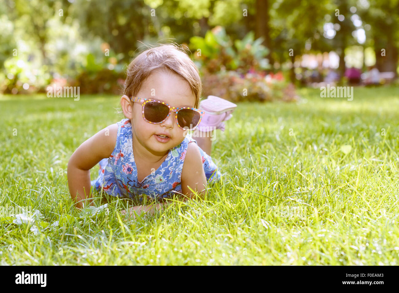 Cute little girl with glasses laying in the grass on a sunny summer day Stock Photo
