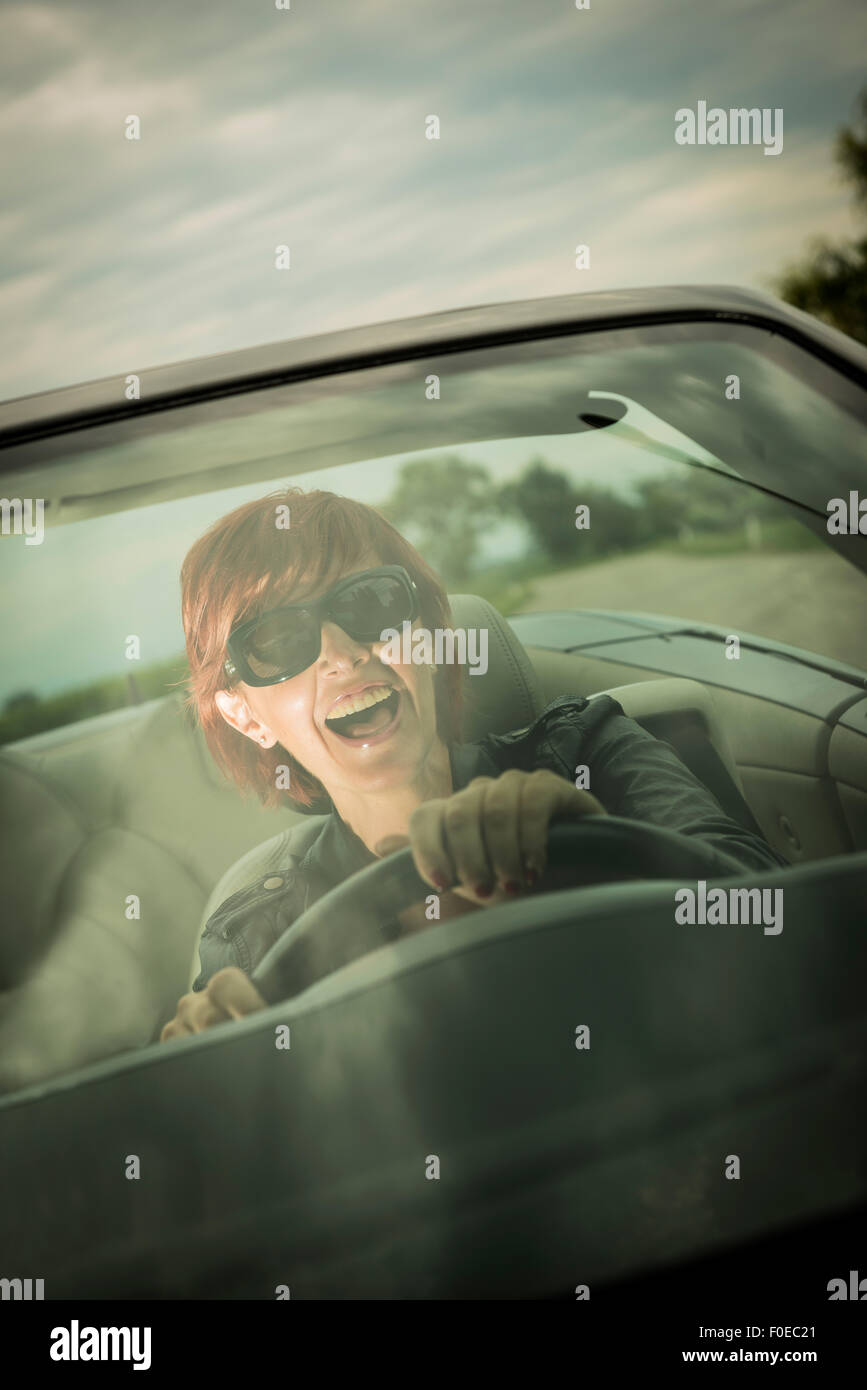 Excited woman enjoying driving her convertible car Stock Photo