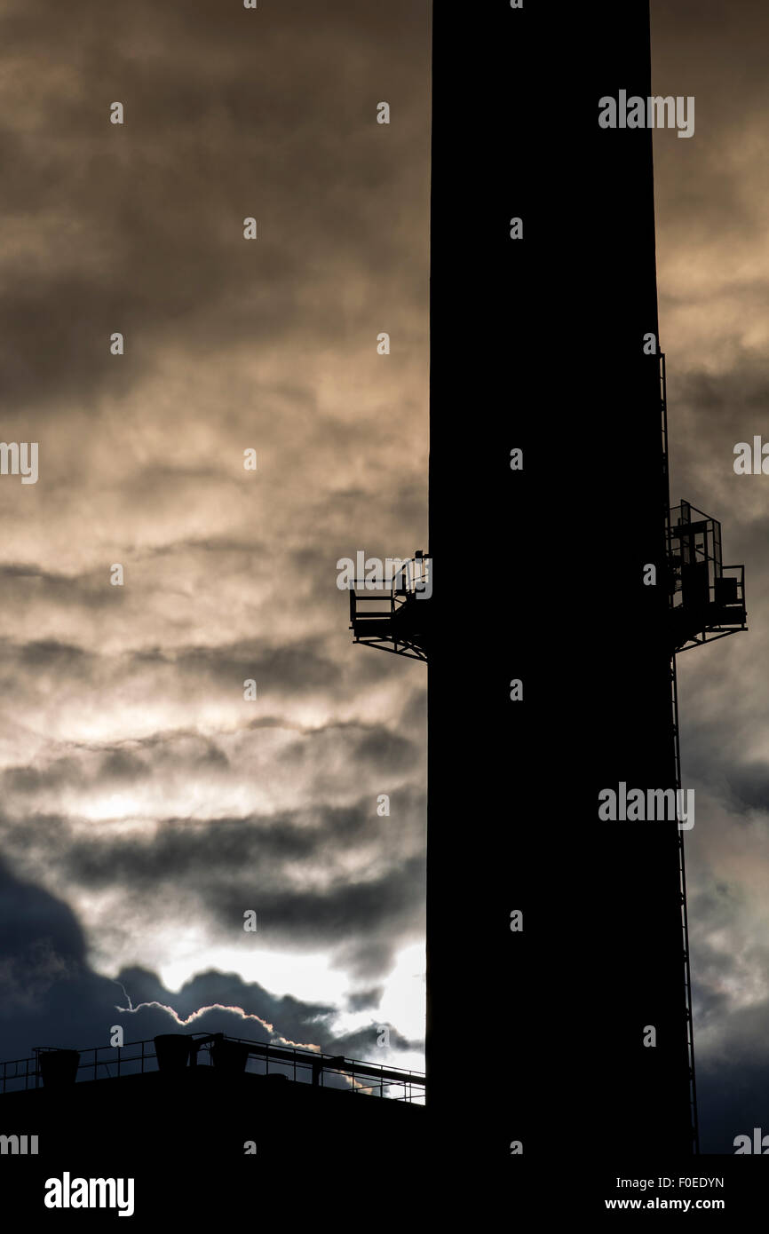 Silhouette of industrial Chimney at twilight morning with strange clouds in the sky. Gdansk, Poland. Stock Photo