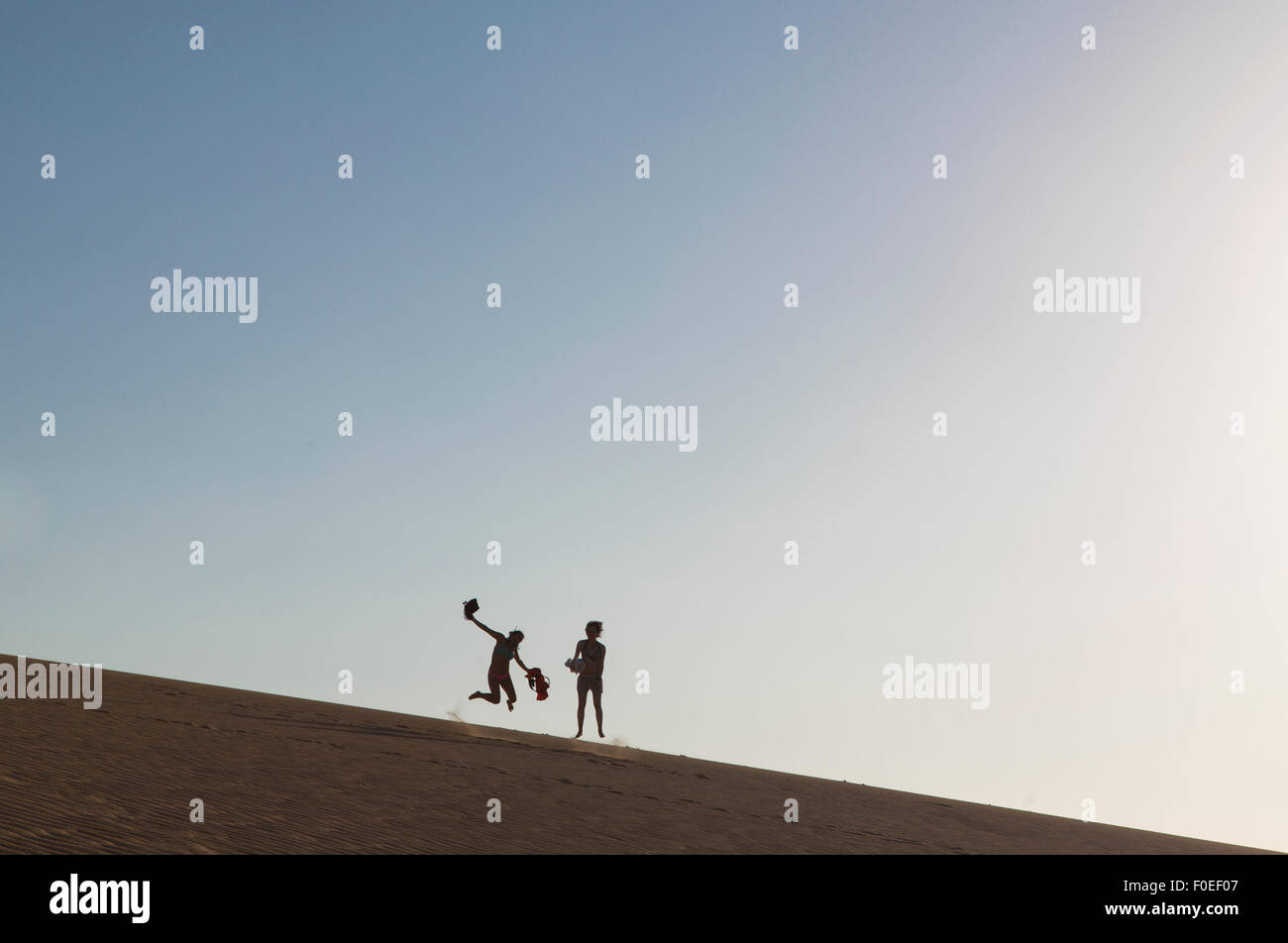 Two girls jumping in the sand of a big dune in La Guajira, Colombia 2014. Stock Photo