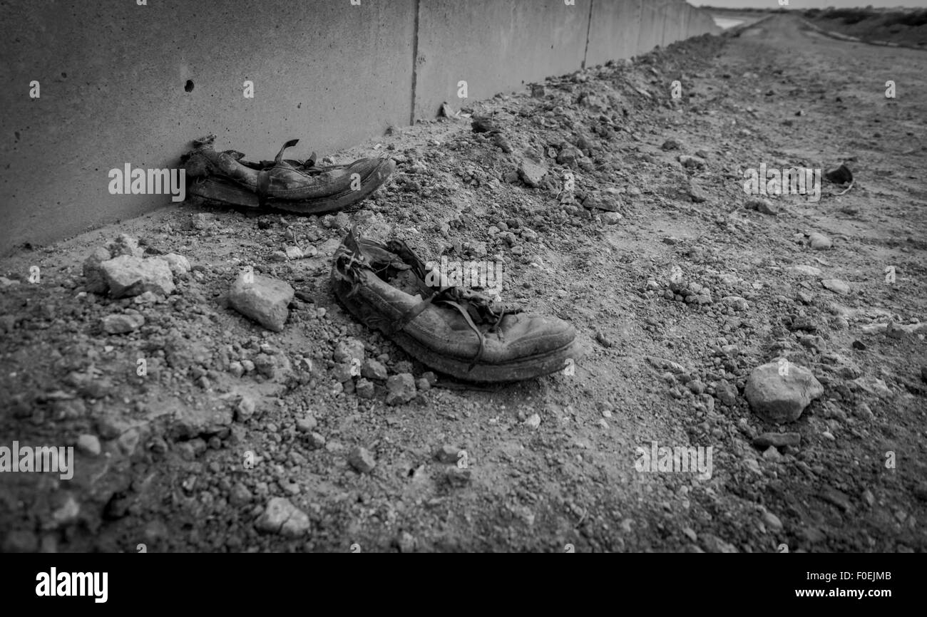 Worn out shoes against wall suggesting end of life journey Stock Photo
