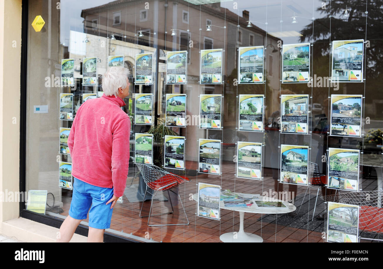 Holidaymaker tourist looking in estate agent window in Prayssac South West France  looking to buy property abroad Stock Photo
