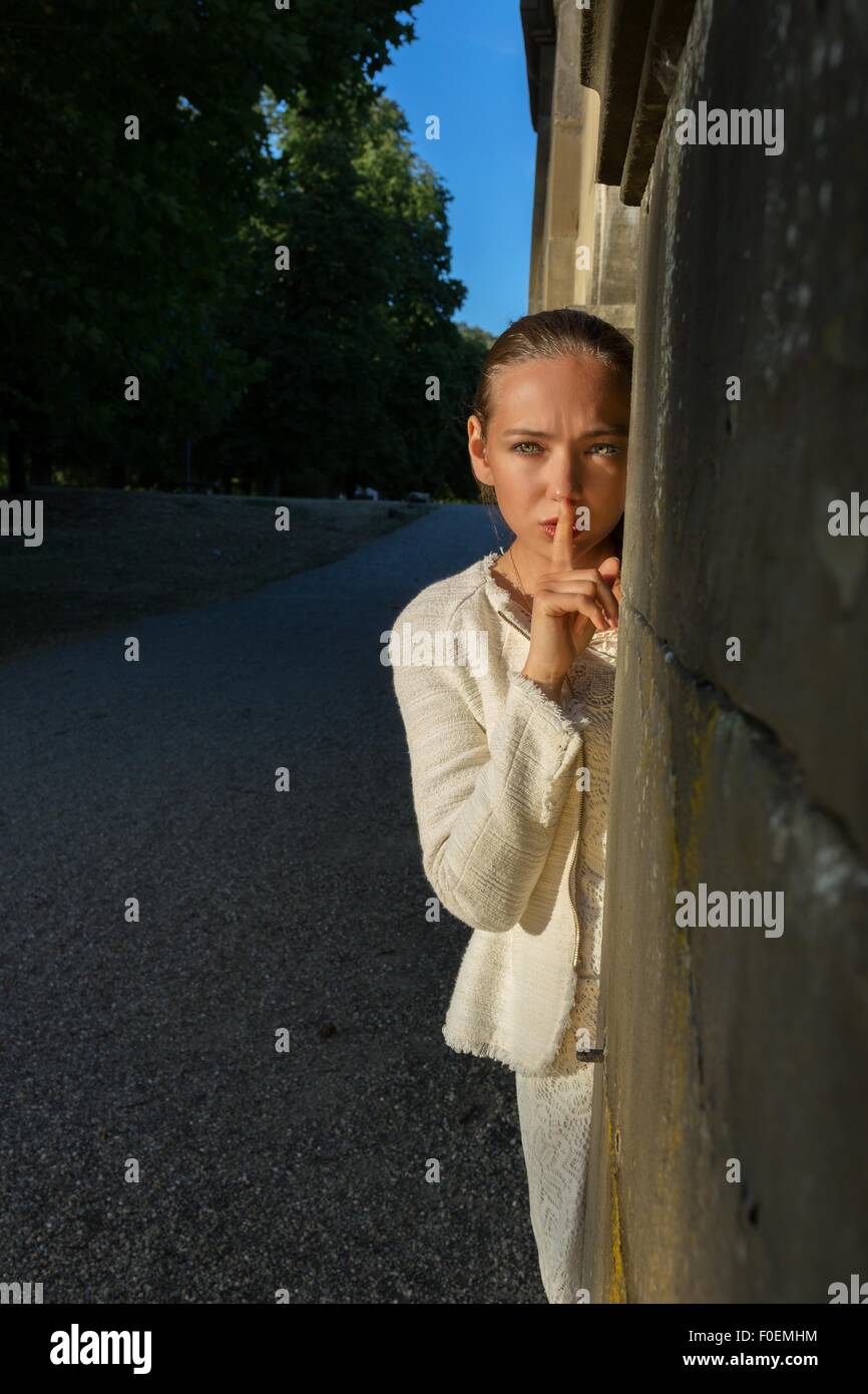 Young woman calling to be silent with index finger in front of her mouth Stock Photo