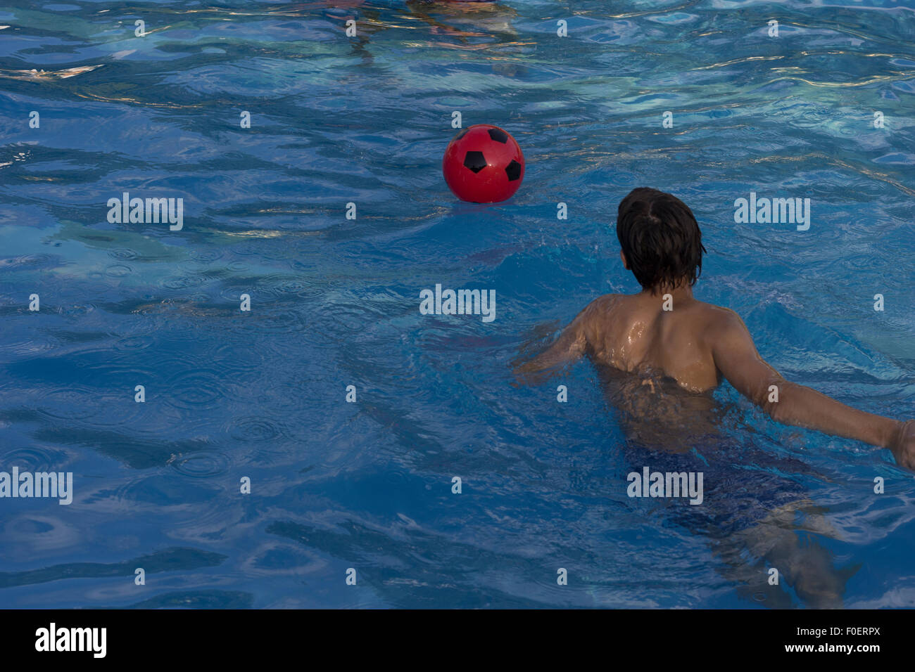 Playing with a red ball in swiming pool Stock Photo