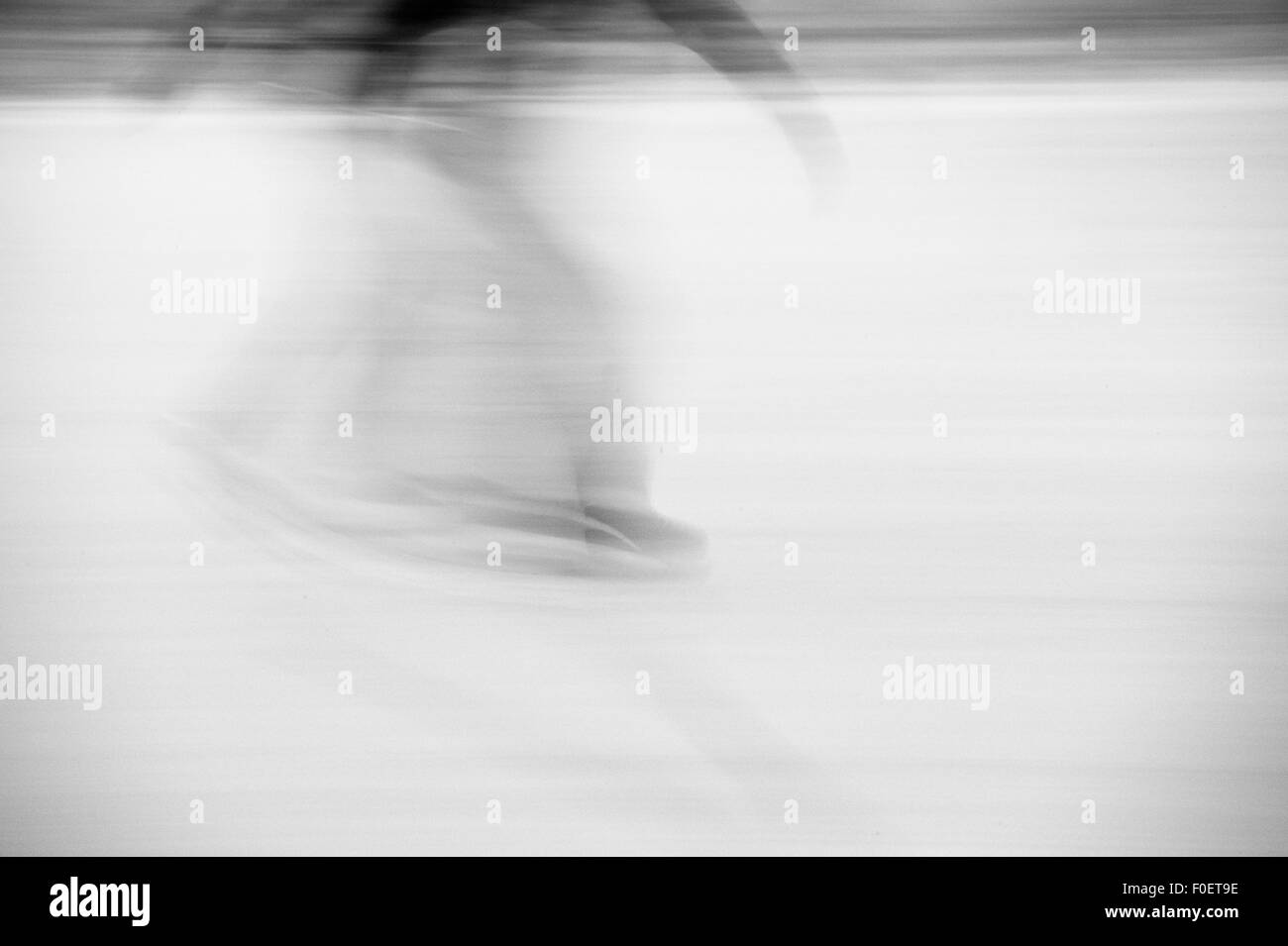 Side view of adult man ice skating in park. Blurred image showing speed and movement. Stock Photo