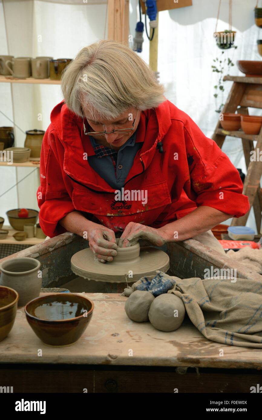 Woman at a potter's wheel demonstrating her skill at a country fair. Stock Photo