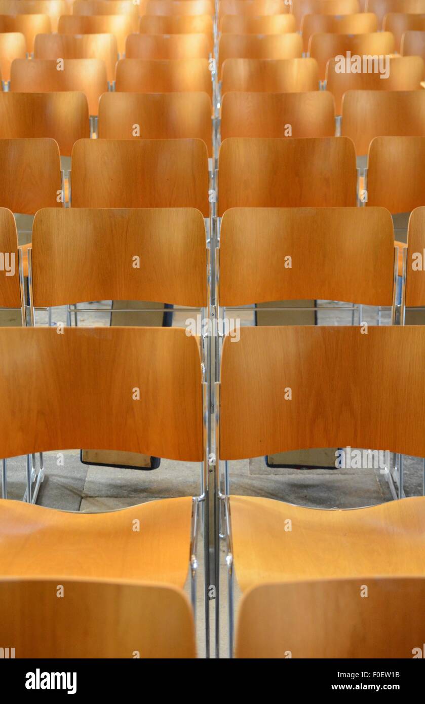 Interlocking wooden chairs in neat rows. Stock Photo