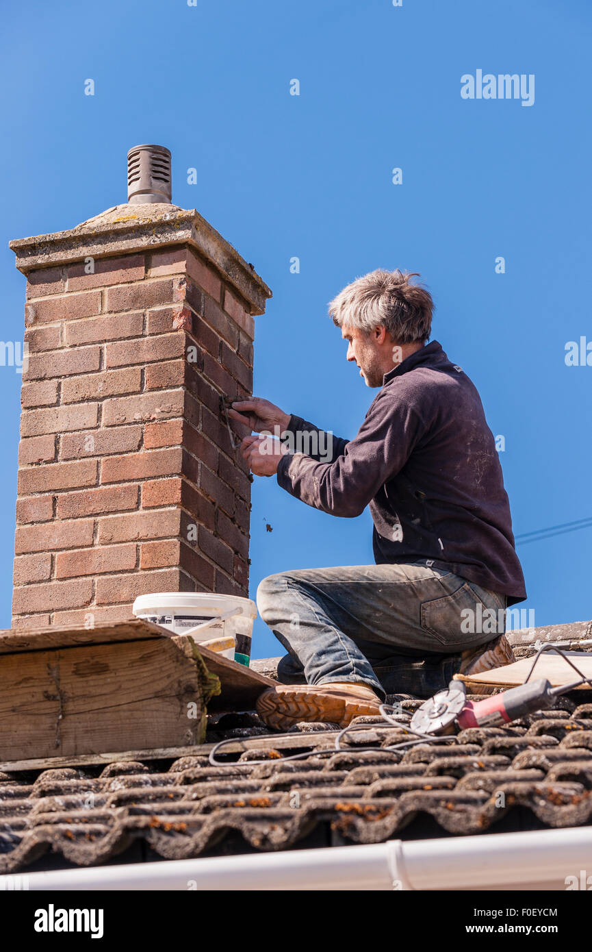 A Builder in the process of repointing a chimney in the UK Stock Photo