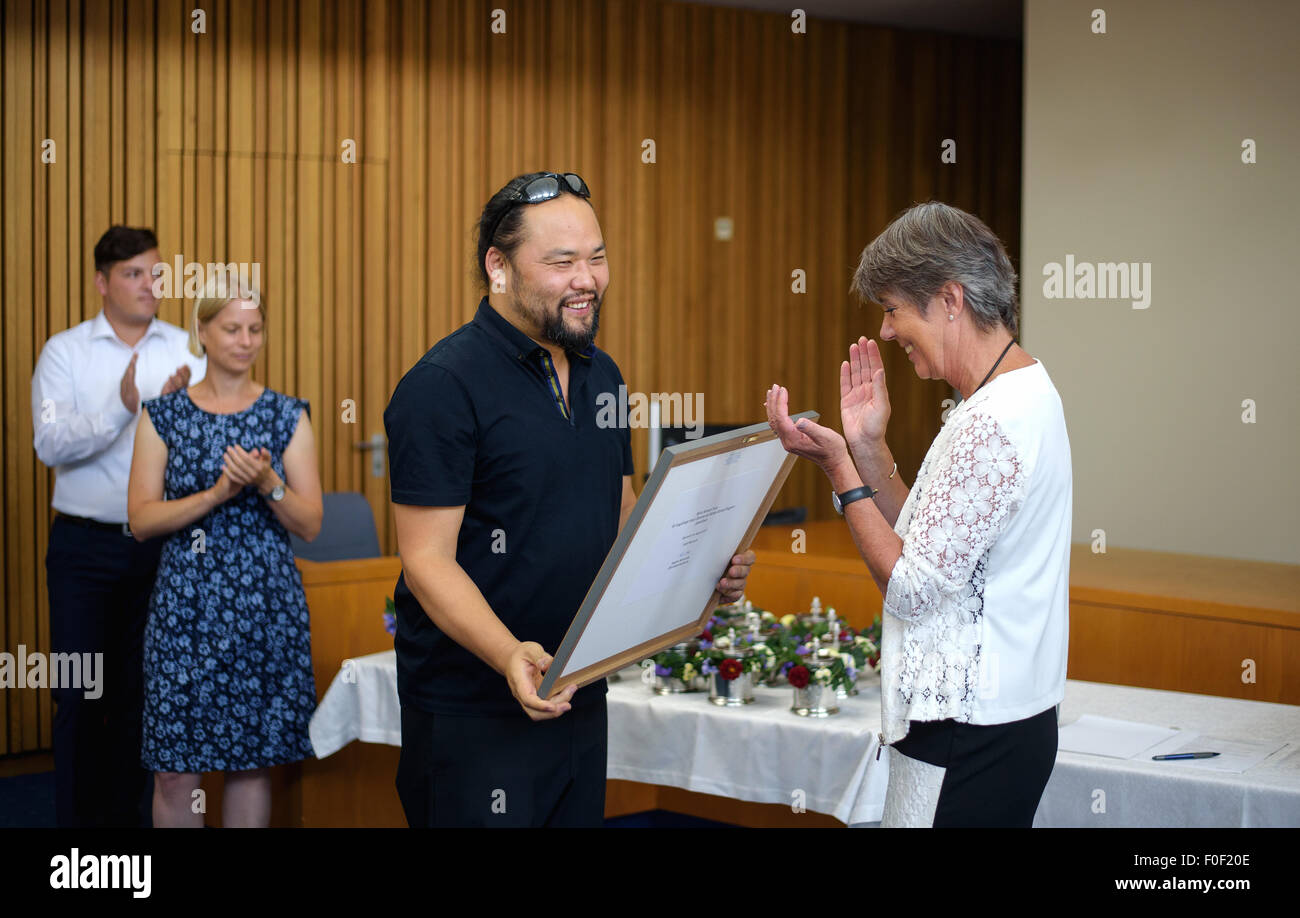 Bayreuth, Germany. 14th Aug, 2015. Soloist Samuel Youn (2-R) receives the die-stamping 'Alt Bayreuth' (lit. Old Bayreuth) from Bayreuths mayor Brigitte Merk-Erbe (R), in consideration of his ten-year collaboration with the Bayreuth Festival in Bayreuth, Germany, 14 August 2015. Photo: Nicolas Armer/dpa/Alamy Live News Stock Photo