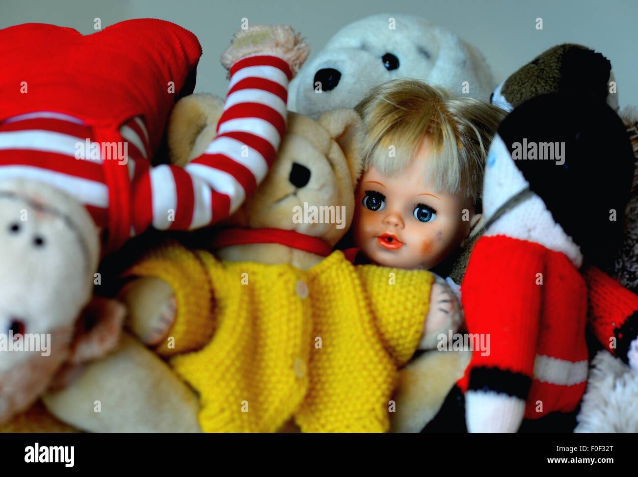 Face of a child's doll in a pile of soft toys Stock Photo