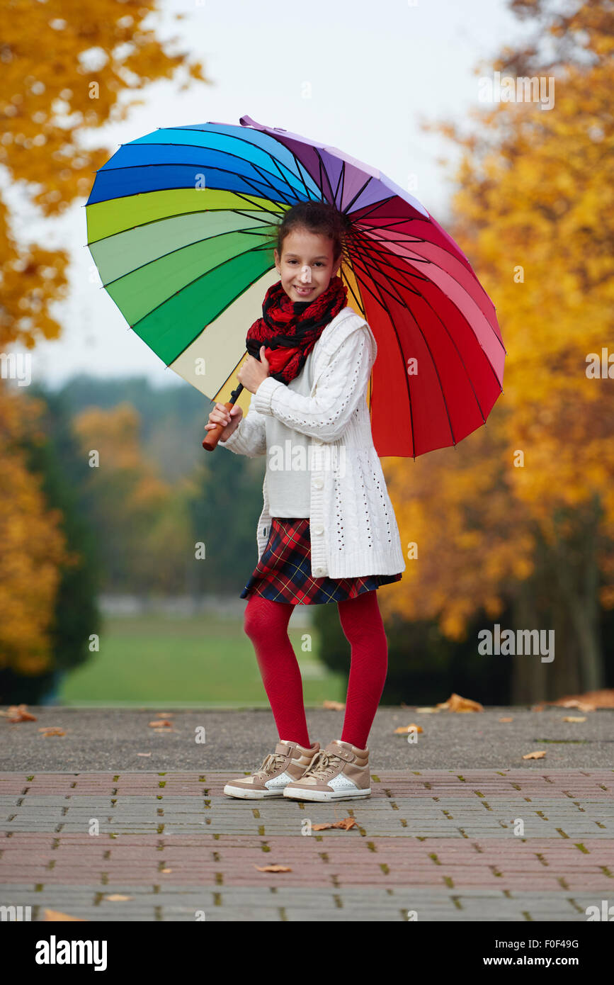 girl under rainbow umbrella in autumn park Stock Photo