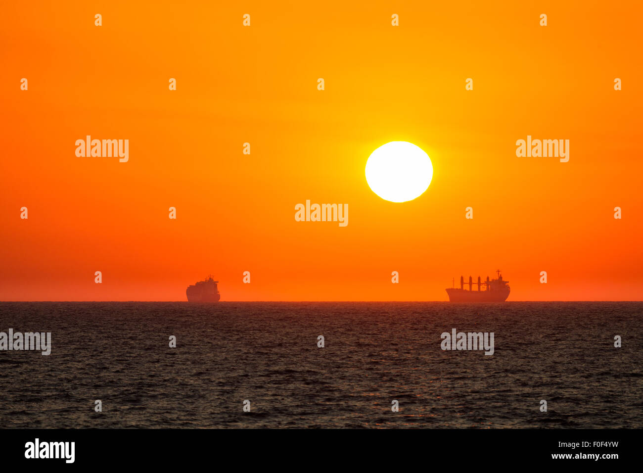 sea sunrise anchored ship Stock Photo
