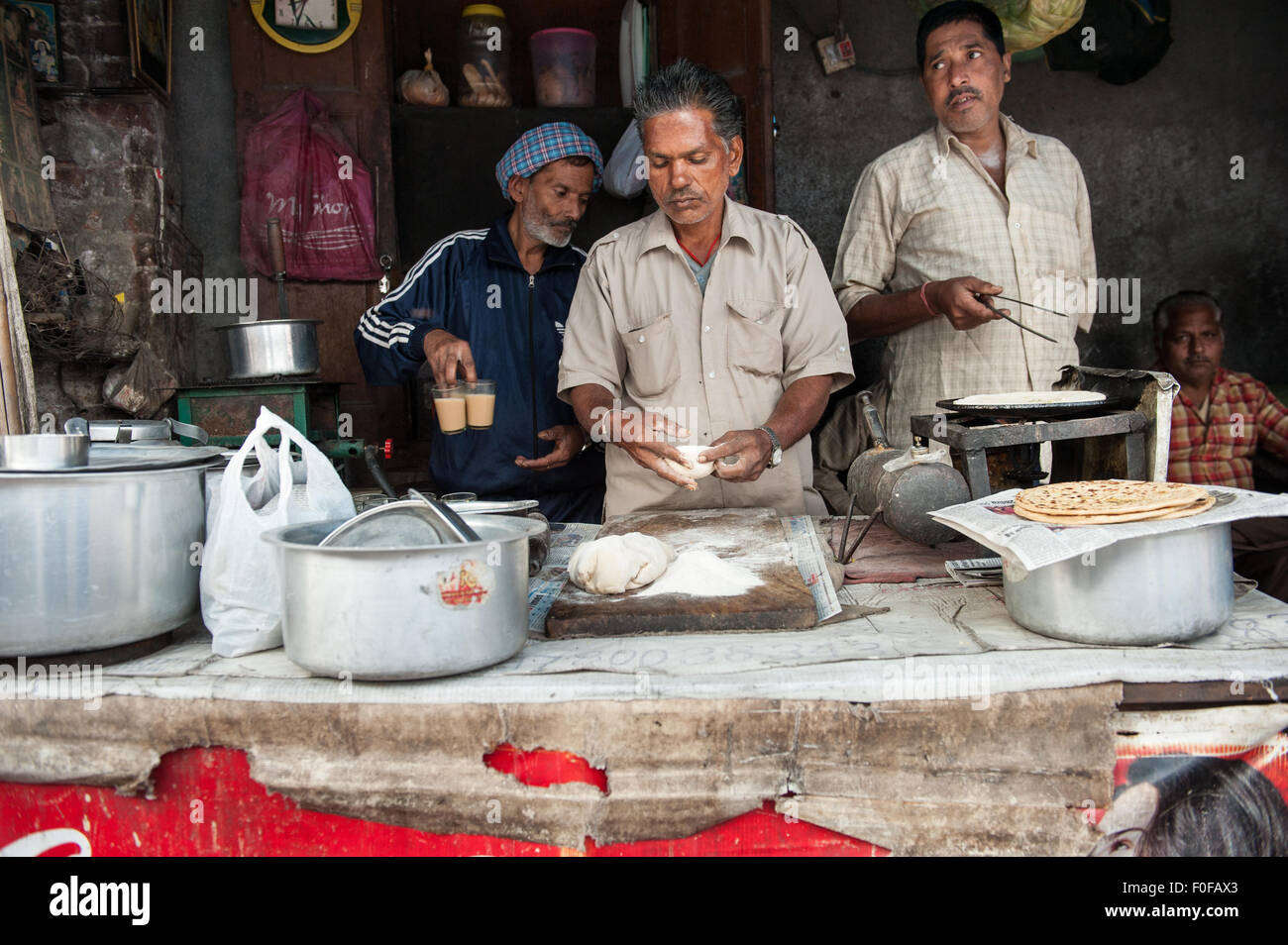 Amritsar, Punjab, India. Three men working at a street food stall, preparing chai tea and chapati bread. Stock Photo