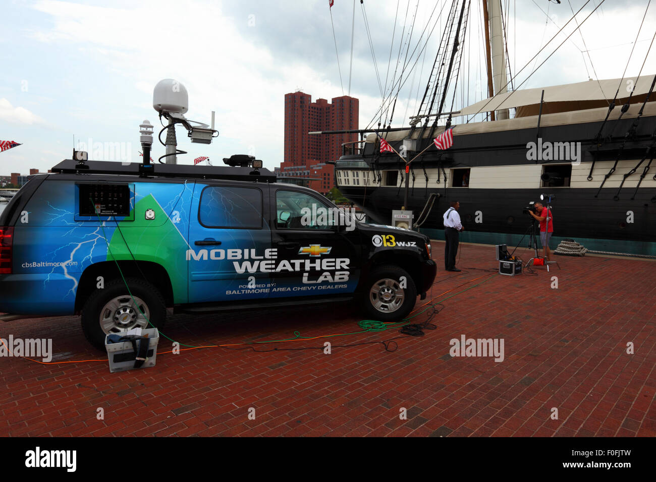 Mobile weather lab vehicle and reporter next to USS Constellation, Inner Harbor, Baltimore City, Maryland, USA Stock Photo