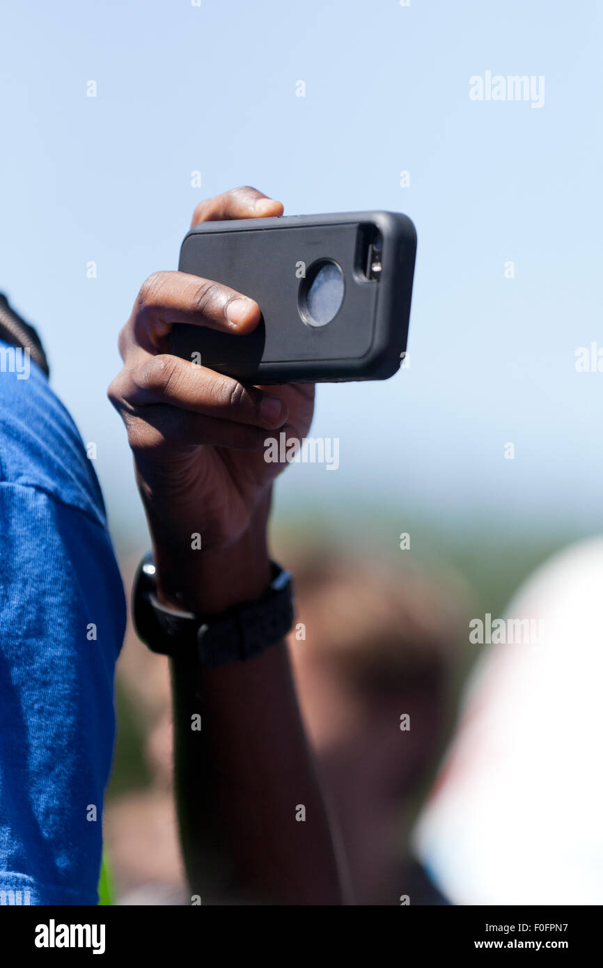 Man using smart phone to video tape an outdoor event - USA Stock Photo