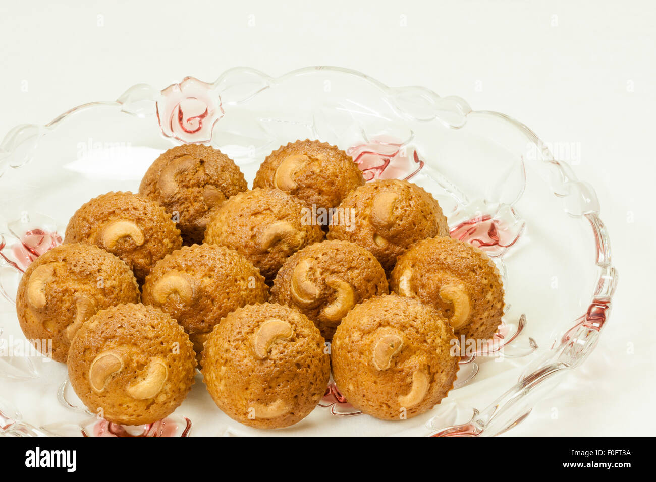 A closeup view of delicious, freshly baked, golden brown crusted cashew cupcakes served on an elegant glass tray. Stock Photo