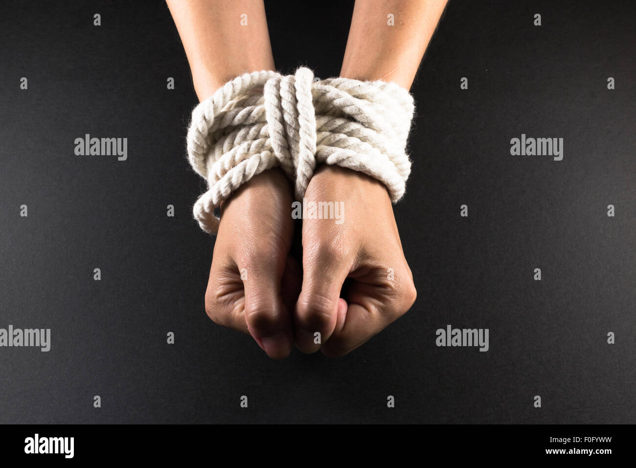 White female hands in bondage tied up with white rope Stock Photo