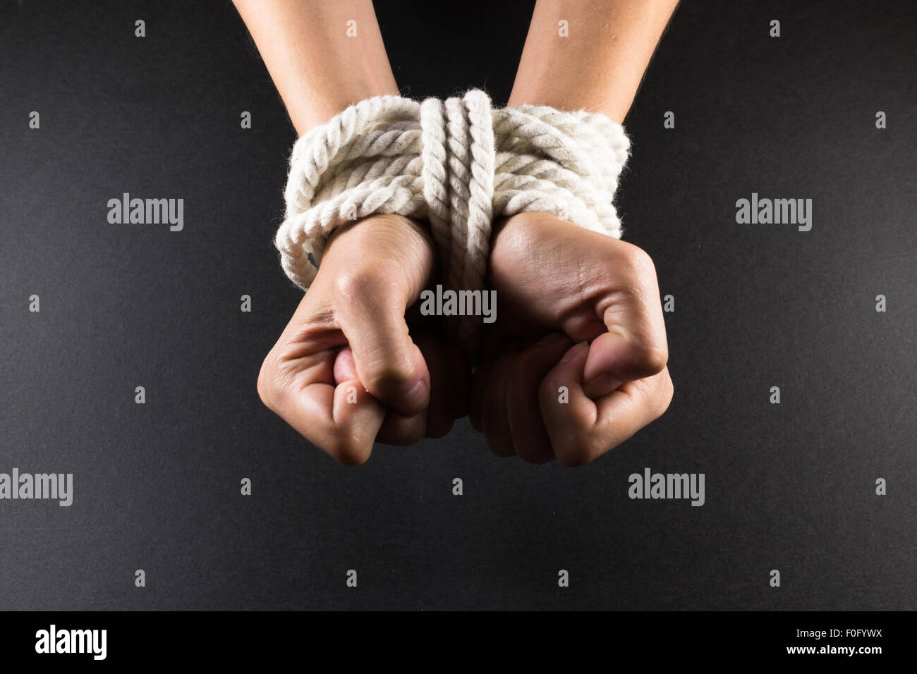 White female hands in bondage tied up with white rope Stock Photo