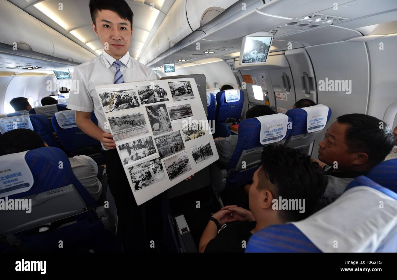 Haikou. 15th Aug, 2015. A flight attendant shows file photos of Anti-Japanese War on flight CZ3119 of China Southern Airlines, Aug. 15, 2015, which marks the 70th anniversary of Japanese unconditional surrender in World War II. China Southern Airlines started an event called 'In Commemoration of the 70th Anniversary of the Victory of China's Anti-Japanese War' on a Haikou-Beijing flight Saturday, which includes reading through file photos, telling stories and quizzes about Anti-Japanese War. Credit:  Zhao Yingquan/Xinhua/Alamy Live News Stock Photo