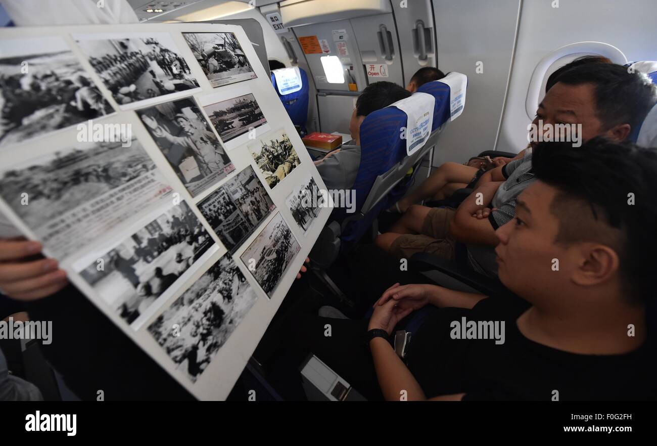 Haikou. 15th Aug, 2015. Passengers look through file photos of Anti-Japanese War on flight CZ3119 of China Southern Airlines, Aug. 15, 2015, which marks the 70th anniversary of Japanese unconditional surrender in World War II. China Southern Airlines started an event called 'In Commemoration of the 70th Anniversary of the Victory of China's Anti-Japanese War' on a Haikou-Beijing flight Saturday, which includes reading through file photos, telling stories and quizzes about Anti-Japanese War. Credit:  Zhao Yingquan/Xinhua/Alamy Live News Stock Photo