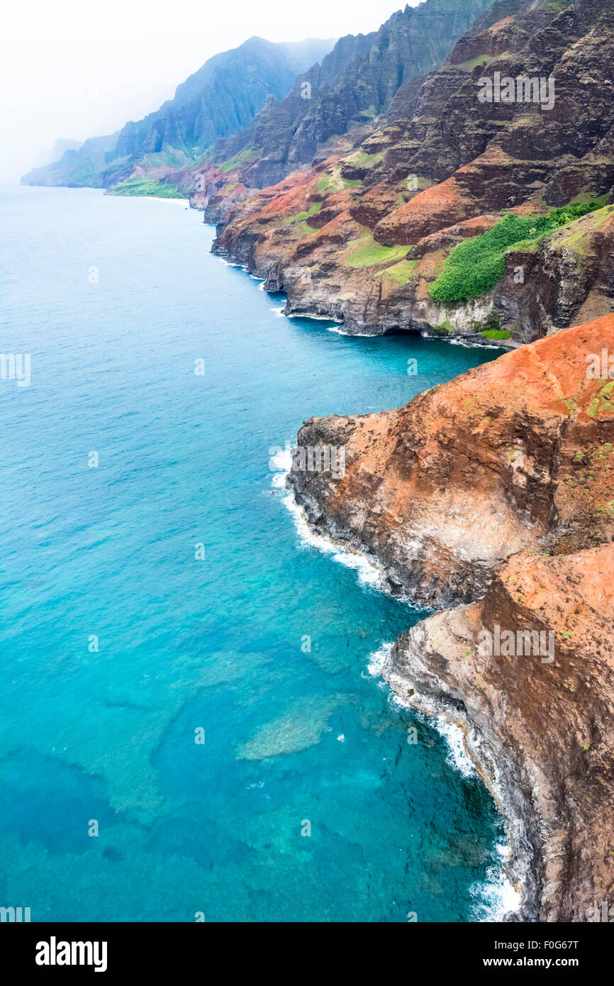 An aerial view of the Na Pali coast in Kauai Hawaii during a vibrant, sunny day shows the rich colors of the scenic coastline. Stock Photo