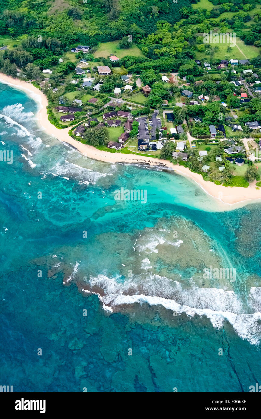 An aerial shot of the Kauai, Hawaii coastline showing the blue water and residential property which lines a small portion of the Stock Photo