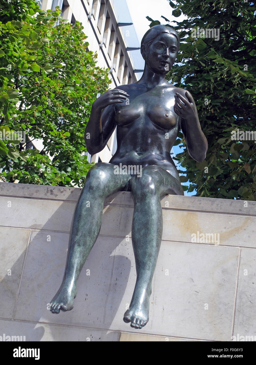 Three girls and a boy by Wilfried Fitzenreiter - Statue by the Spree River, Moabit, Berlin, Germany with building behind Stock Photo