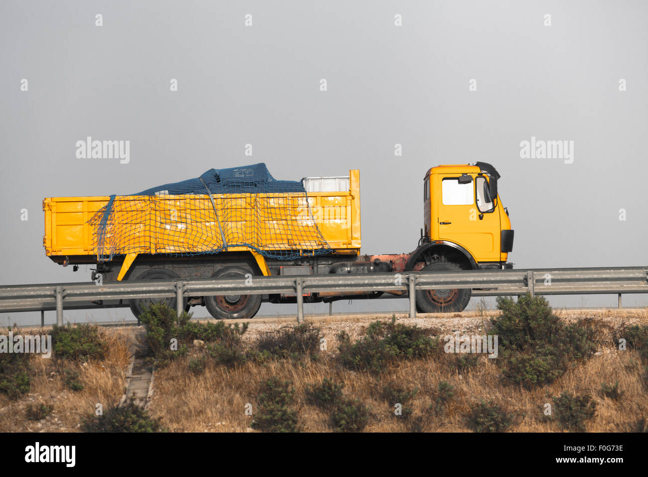 Yellow dump truck on the road with grey sky Stock Photo - Alamy