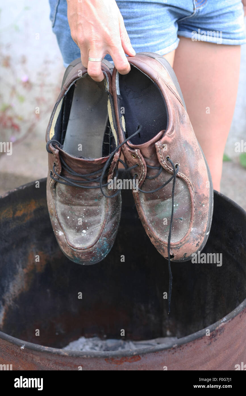 Young woman dumps her father's old work shoes. Stock Photo