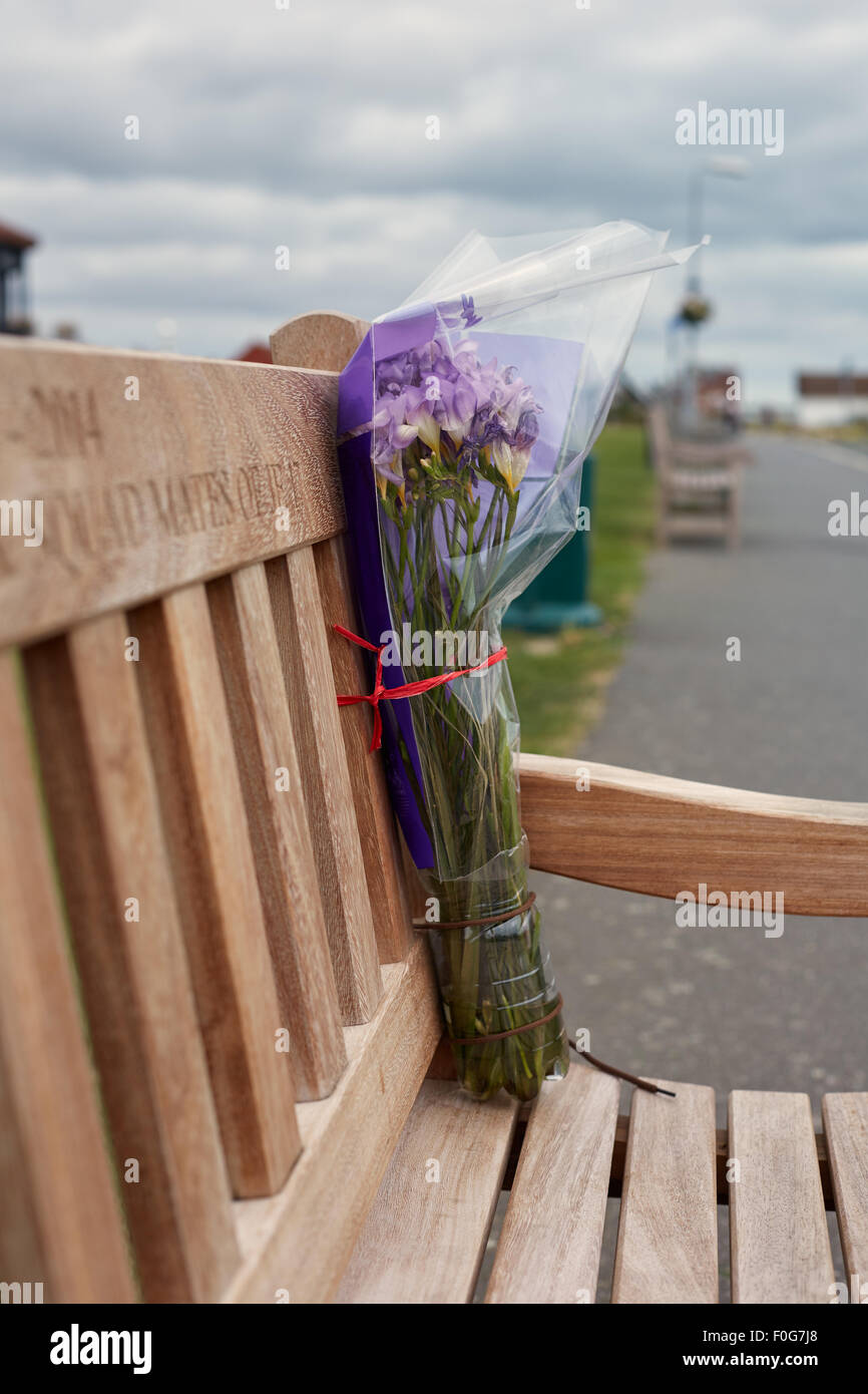 A bunch of flowers left on a bench for remembrance of someone deceased. Stock Photo