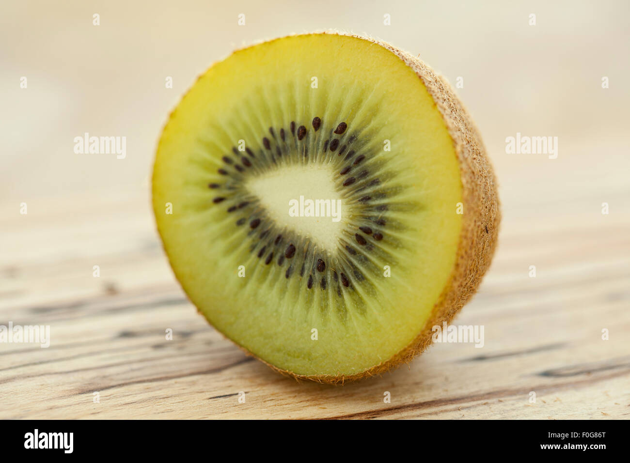 A sliced kiwifruit or kiwi on a wooden surface photographed with window light. Stock Photo