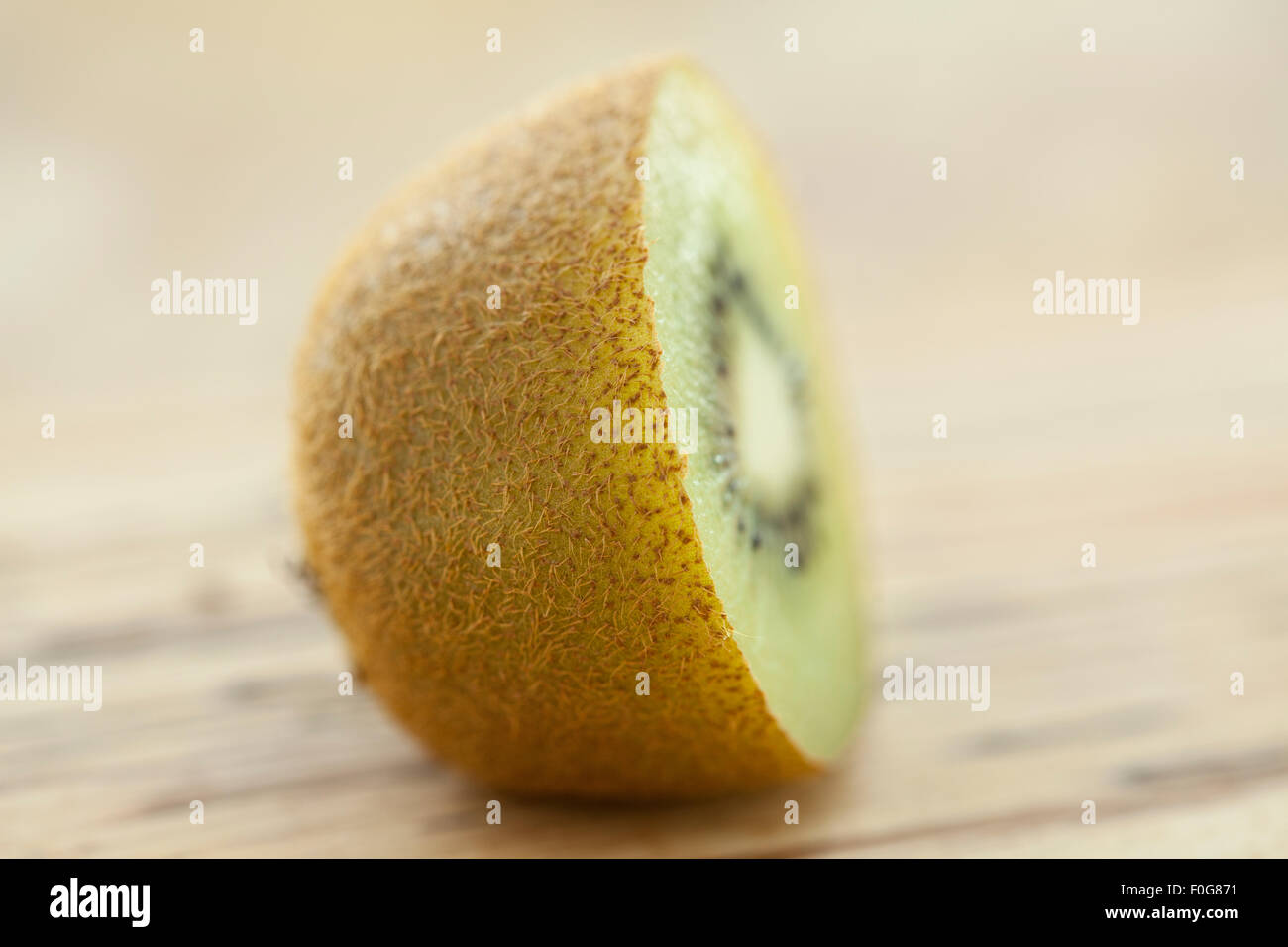 A sliced kiwifruit or kiwi on a wooden surface photographed with window light. Stock Photo
