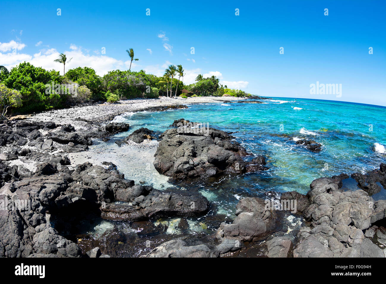A beautiful black and white gravel beach with clear blue water on a remote beach in Kona Hawaii. Stock Photo