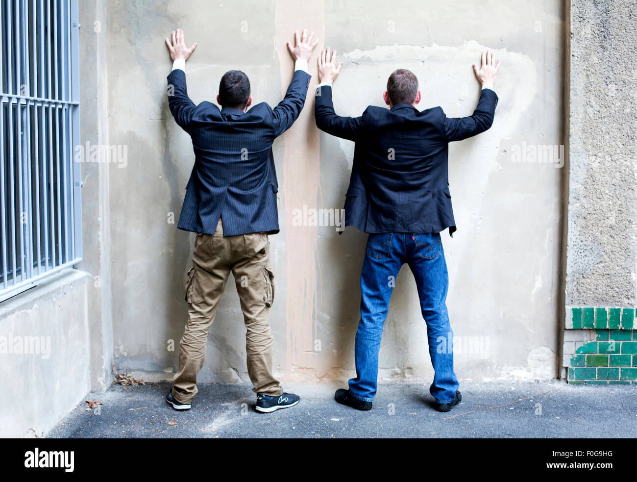two men in jackets standing against a wall Stock Photo