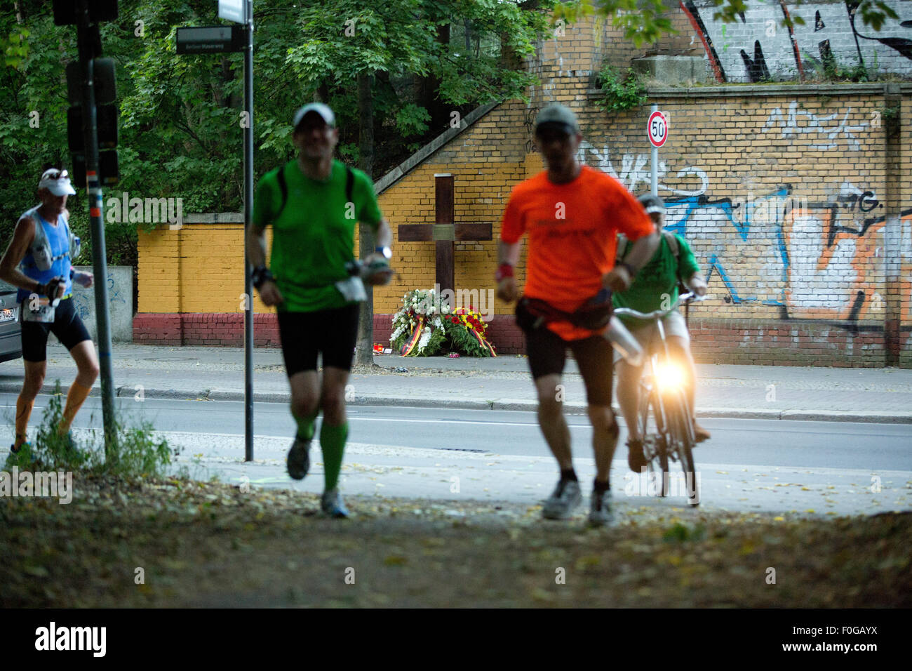 Berlin, Germany. 15th Aug, 2015. Participants of the 100 mile run '100MeilenBerlin' run along the former Berlin Wall path and pass the memorial cross for Horst Frank, who lost his life due to the Wall, in Berlin, Germany, 15 August 2015. Athletes run a distance of 160, 9 kilometres to commemorate the building of the Wall 54 years ago. Photo: Joerg Carstensen/dpa/Alamy Live News Stock Photo
