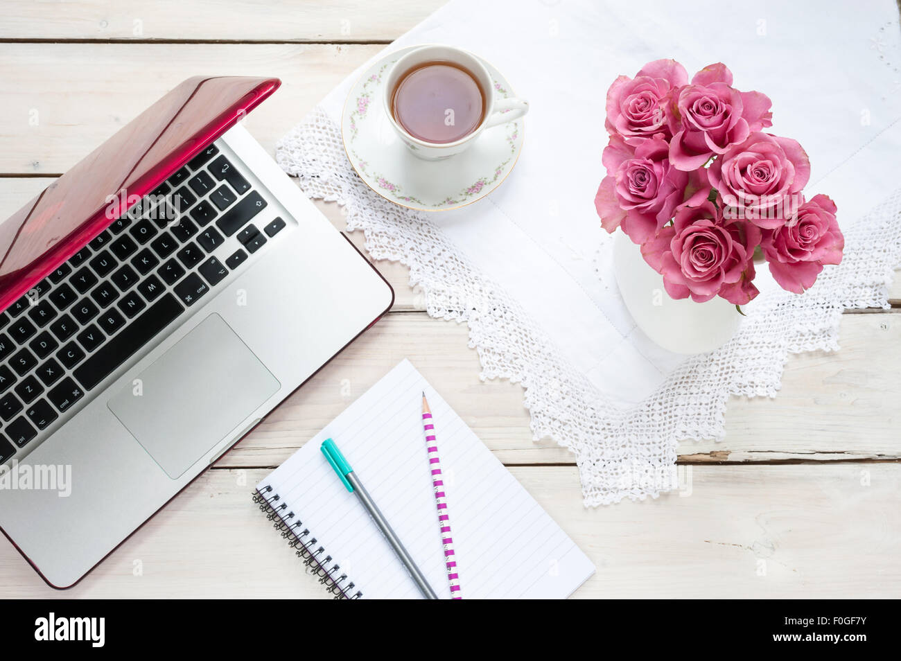 working from home laptop, pink roses, teacup, notebook and pens on a desk Stock Photo Alamy