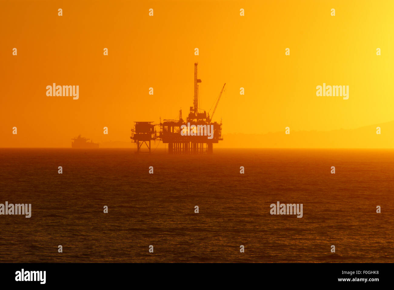 Beach Off-shore Oil Rig at Sunset Stock Photo