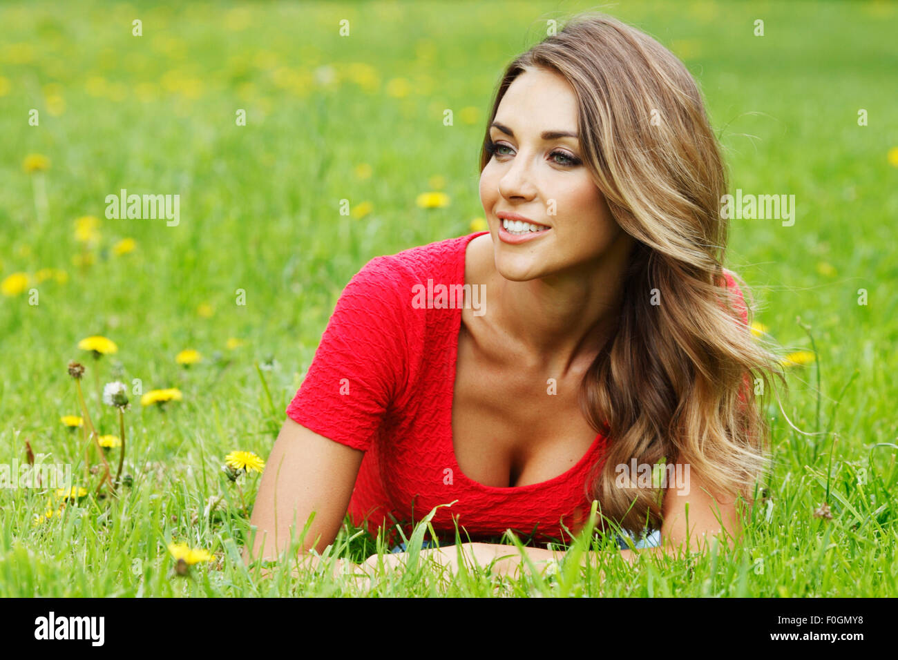 young woman in red dress lying on grass Stock Photo - Alamy