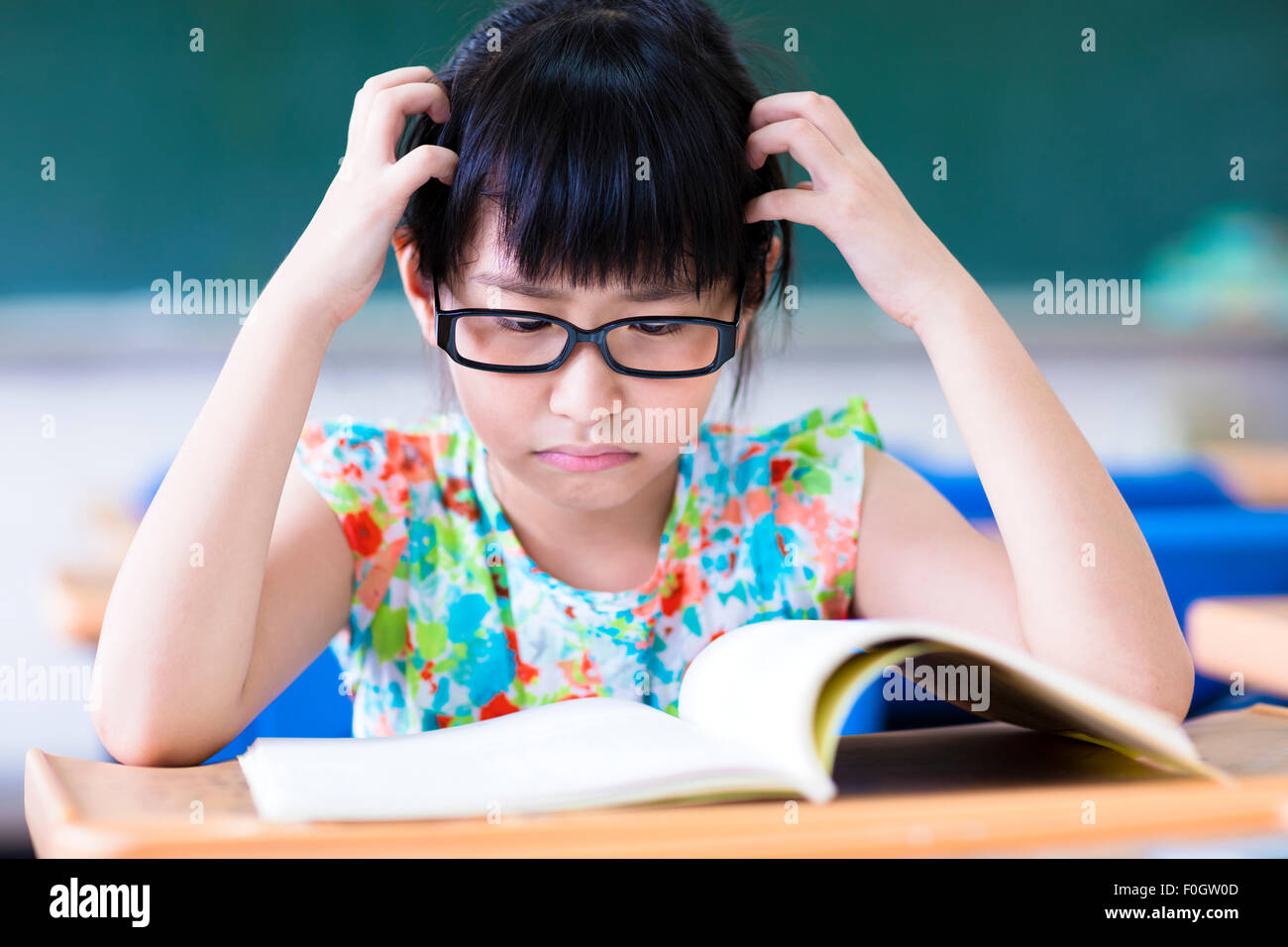 Depressed little girl studying in the classroom Stock Photo