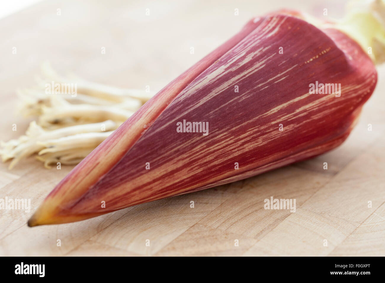 A banana blossom or banana heart photographed on a wooden surface with