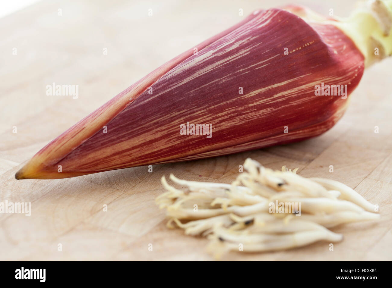 A banana blossom or banana heart photographed on a wooden surface with