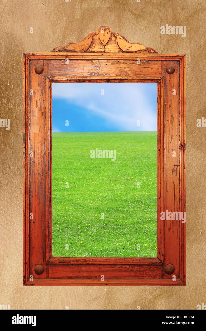 ancient carved wooden frame with idyllic natural photo on it - could be a window Stock Photo