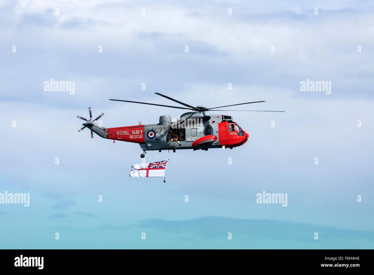 A Royal Navy Search and Rescue helicopter flying the White Ensign off the northeast coast of the United Kingdom. Stock Photo