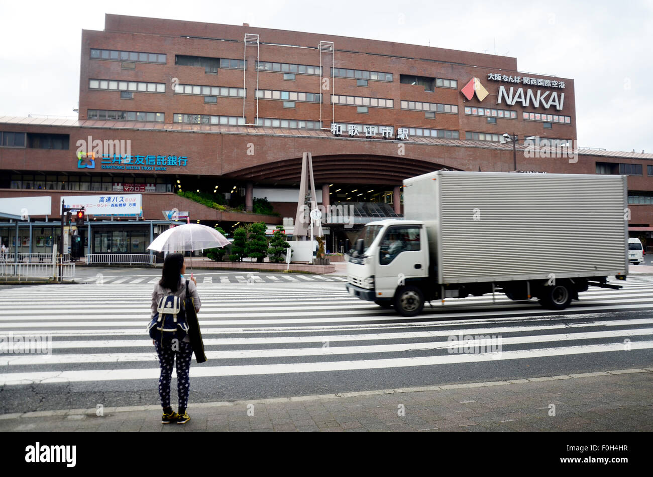 Thai woman holding umbrella while raining and wait cross over road at crosswalk front of Kintetsu Nara station on July 7, 2015 Stock Photo