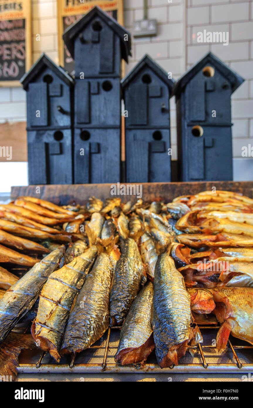 A selection of smoked fish in front of bird boxes styled on the net huts of Hastings. East Sussex. UK Stock Photo
