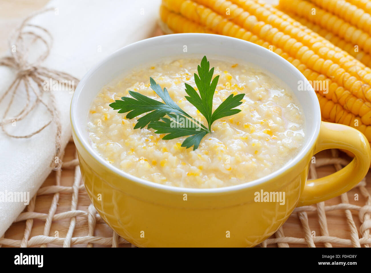 Brazilian corn soup canjiquinha in yellow bowl with fresh corn