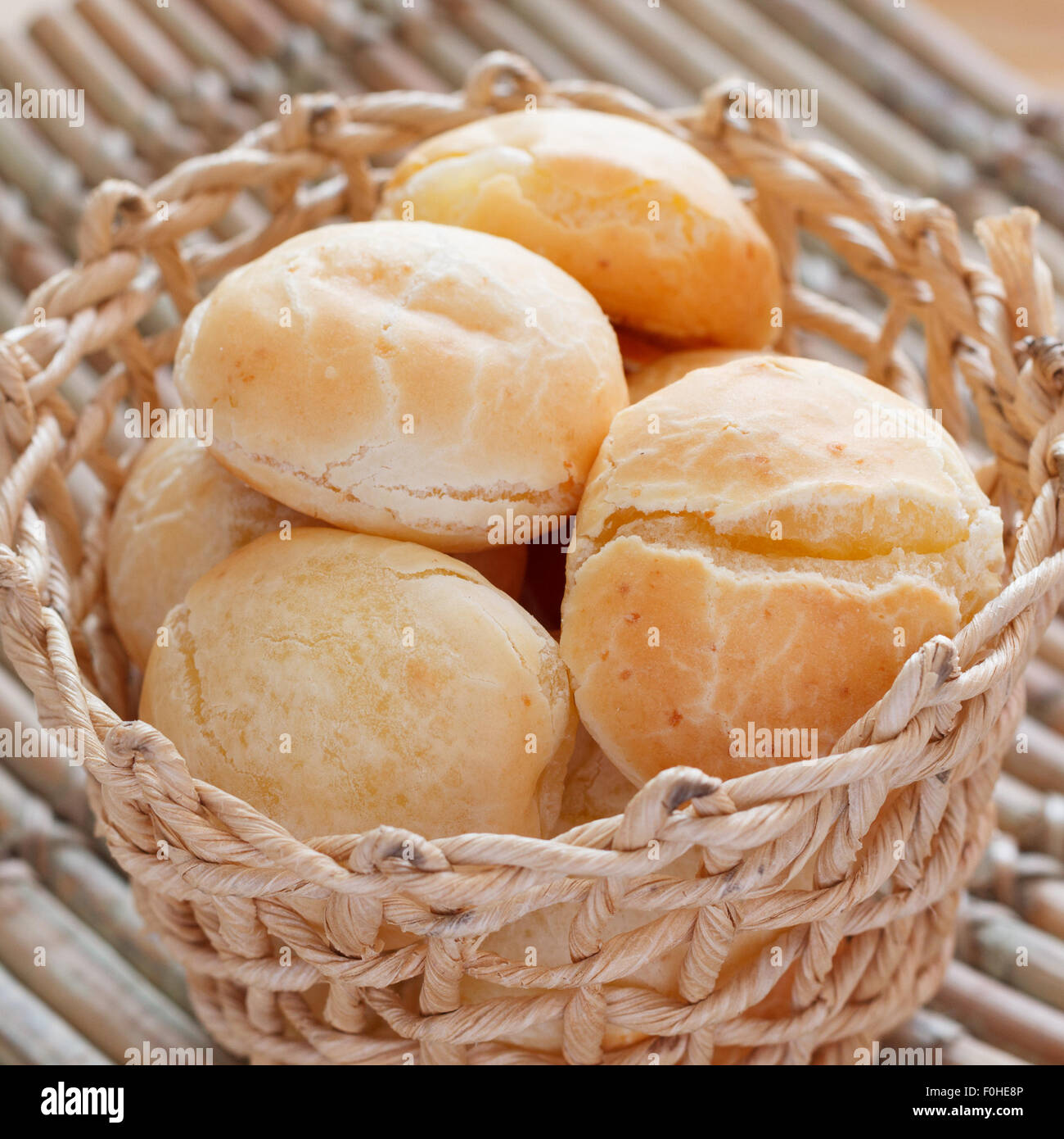 Brazilian snack cheese bread (pao de queijo) in wicker basket on wooden table. Selective focus Stock Photo