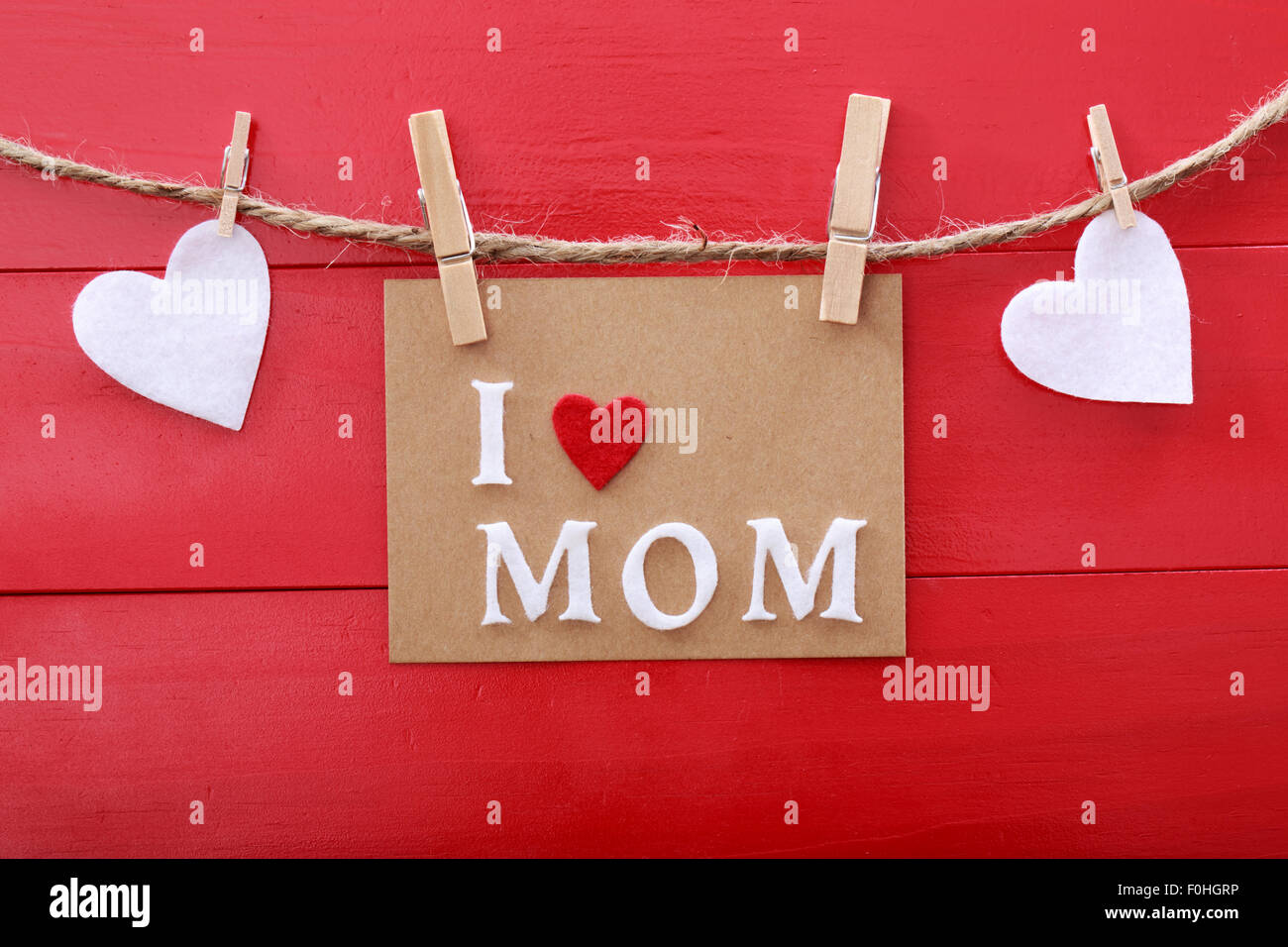 Mothers day message with felt hearts hanging with clothespins over red wooden board Stock Photo