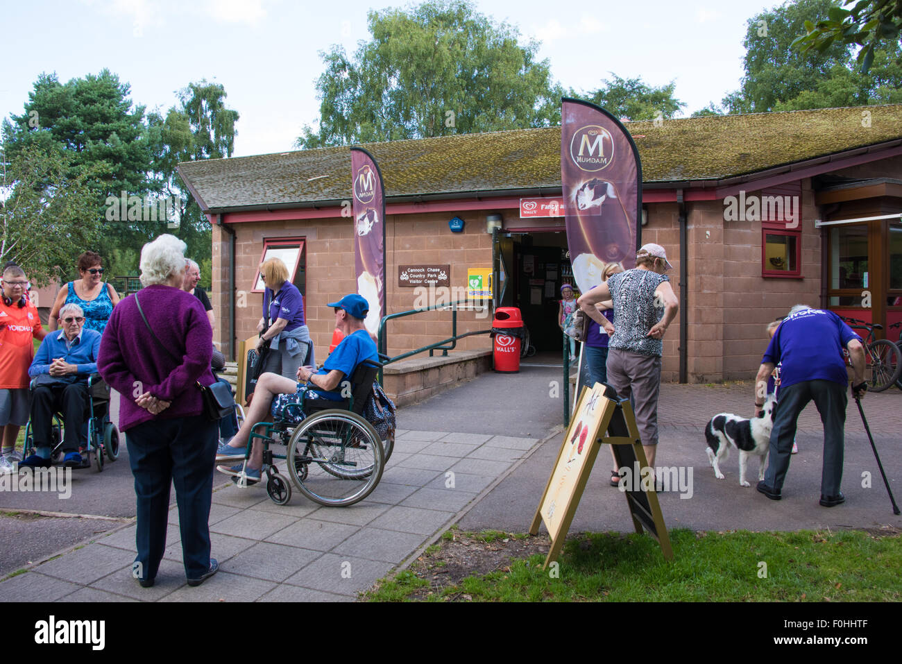 Two Men in Wheelchairs and people outside the Entrance to the Cafe at